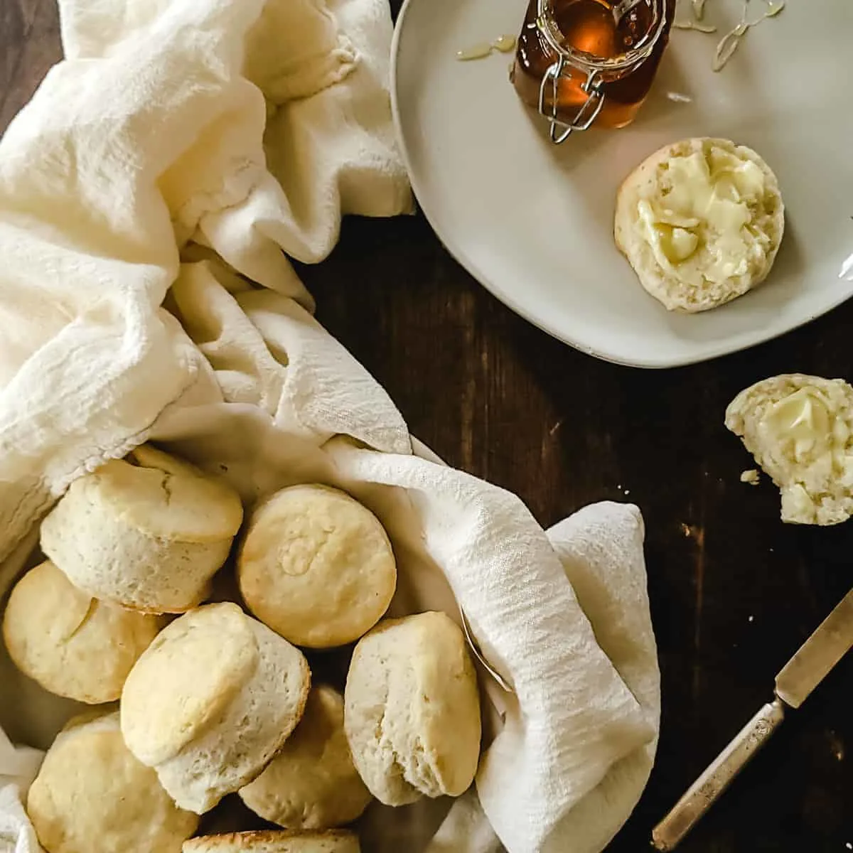 A basket of biscuits with butter and honey.