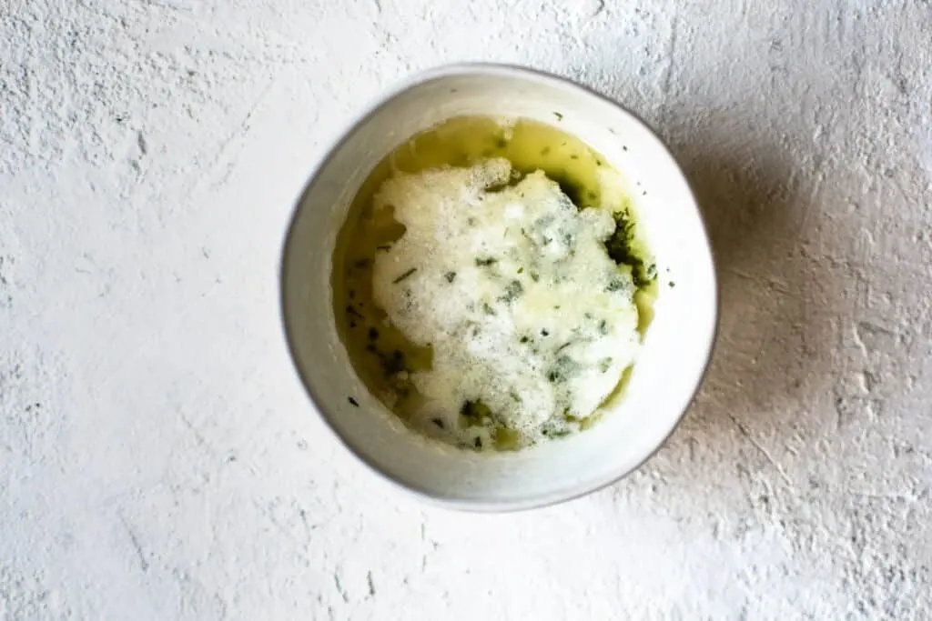 bowl of melted butter mixed with herbs and garlic powder