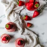 strawberry cupcakes topped with fresh strawberries on white marble counter
