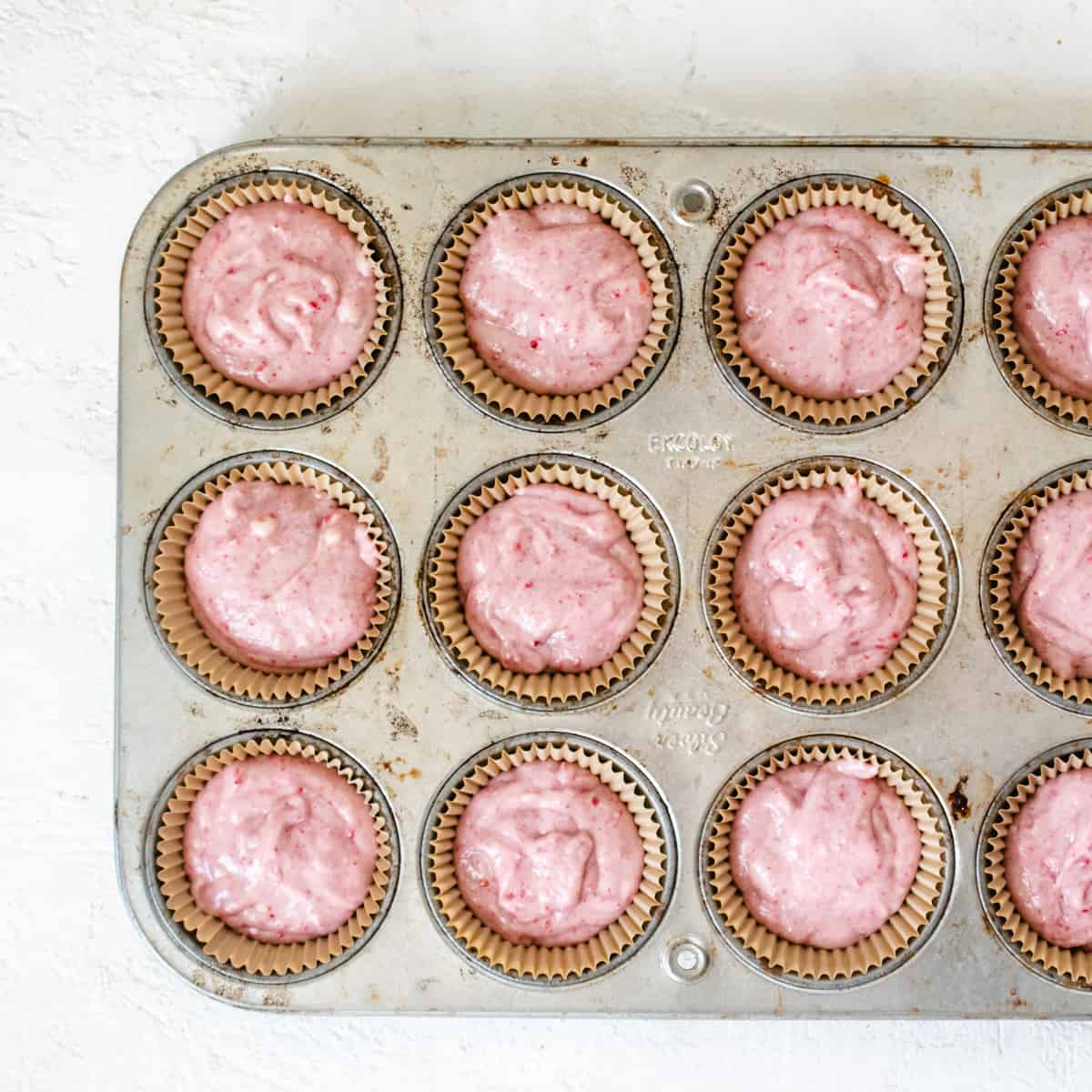 Cupcake tin filled with pink batter.