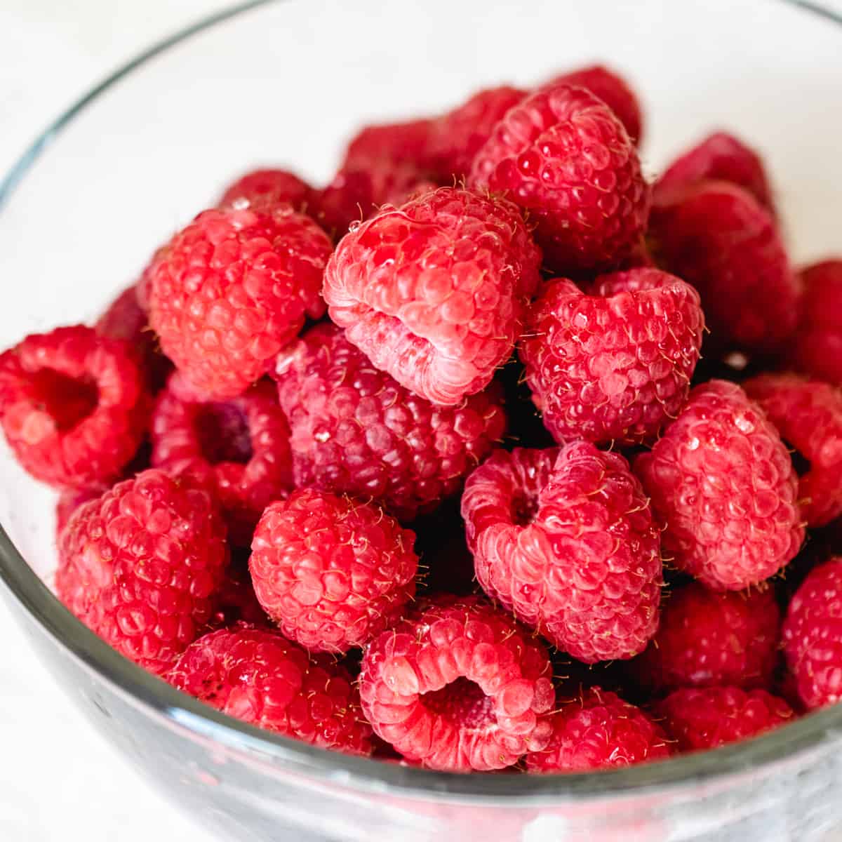 A glass bowl of fresh raspberries.