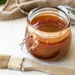 apricot bbq sauce in a glass jar with a basting brush