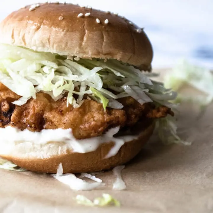 crispy chicken sandwich on a sesame seed bun with mayonnaise and shredded lettuce