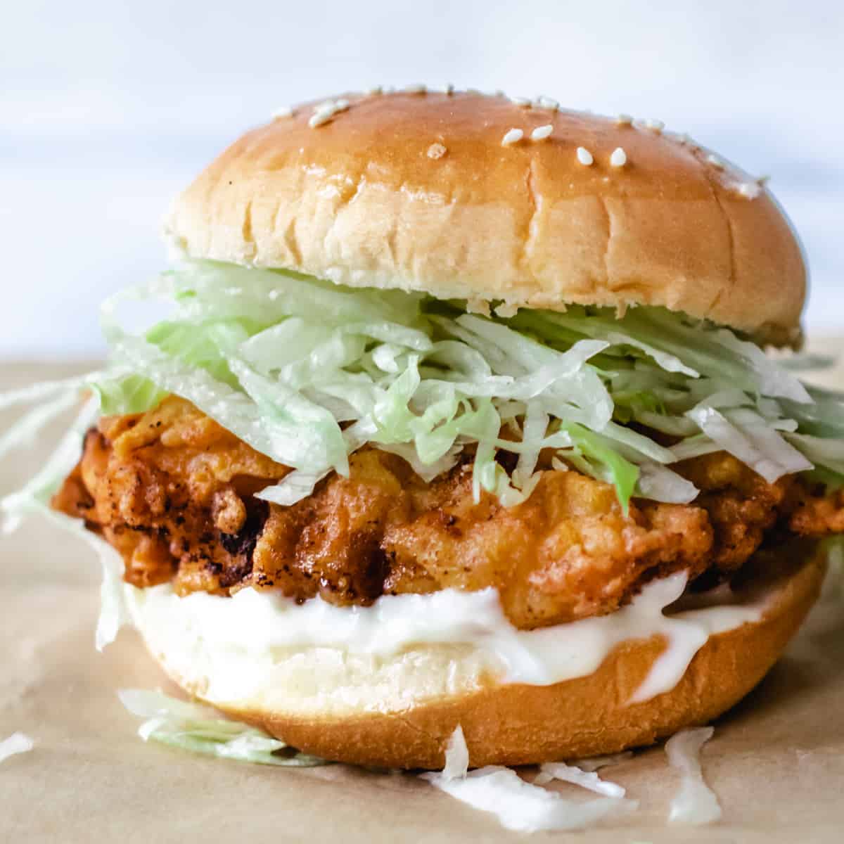 Fried chicken patty on a sesame seed bun with finely shredded ice burg lettuce and mayonnaise. 