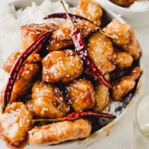 Deep fried pieces of chicken in a light sauce with white rice in a bowl.