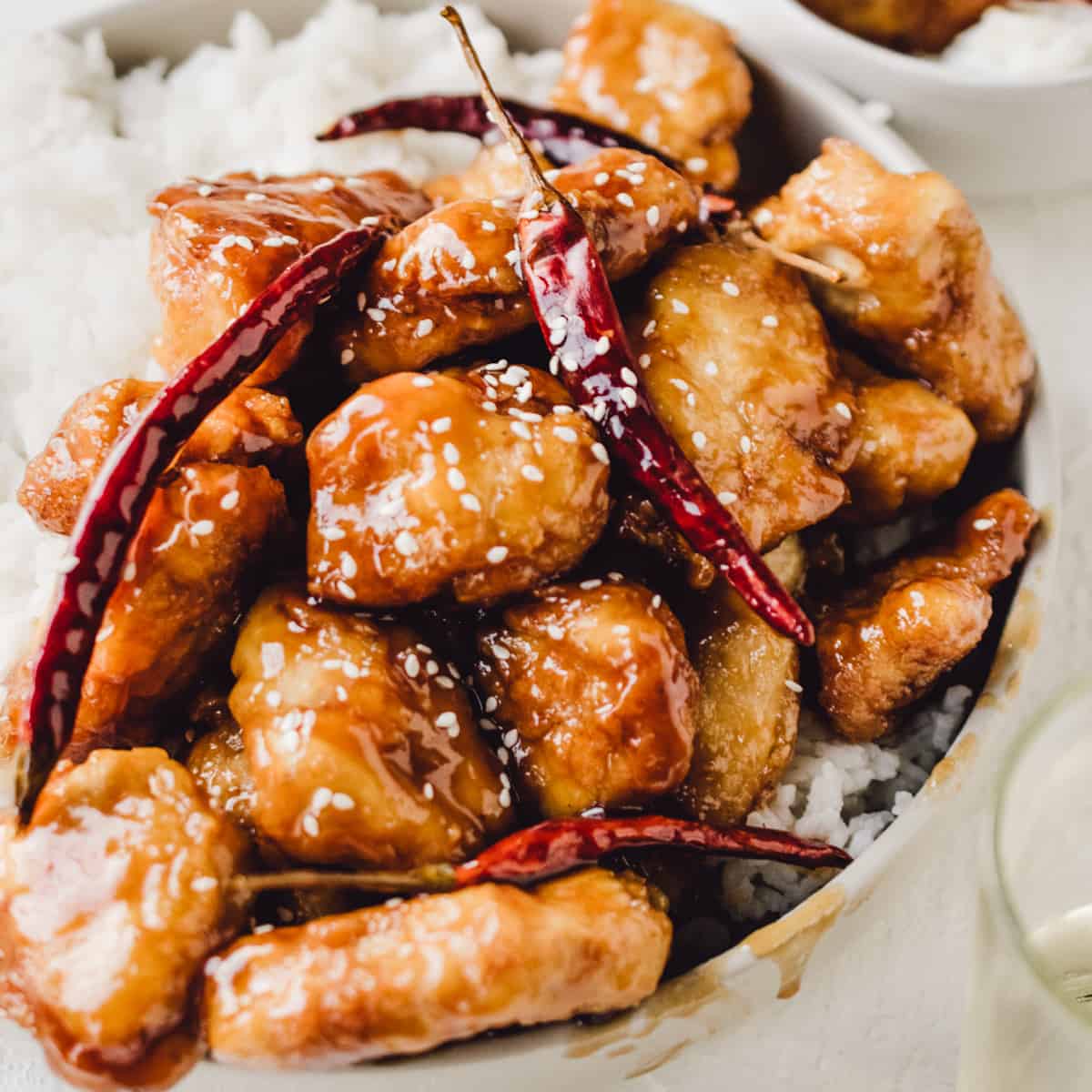 Gluten free fried chicken pieces in a general Tso sauce with chili pods.