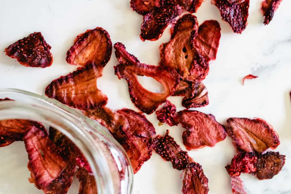dehydrated strawberries and a jar on a marble counter top