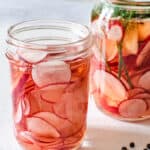 2 jars of pickled radishes, one with added herbs and peppercorns