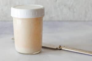 A mason jar with a plastic lid to store homemade spicy mayonnaise in the fridge.