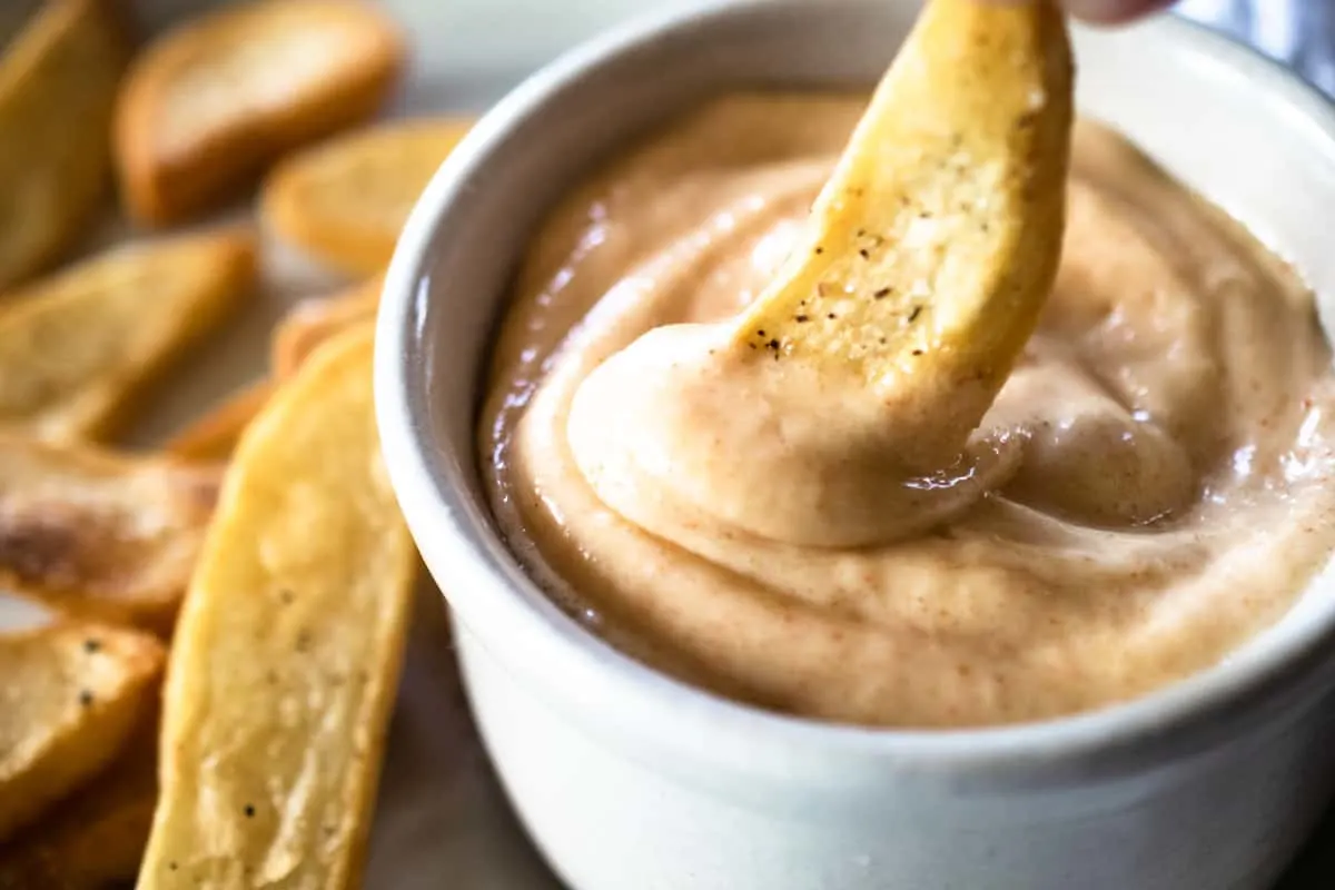 ramekin of spicy mayo with a french fry dipped in
