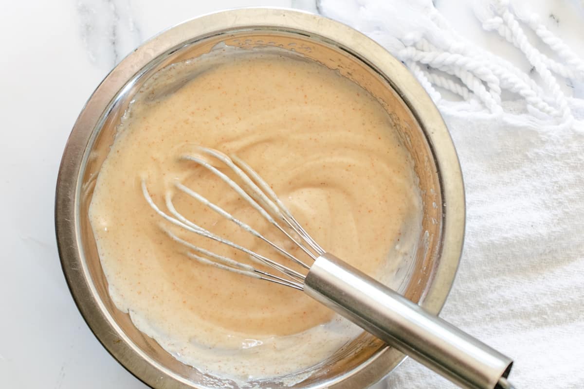 Bowl of homemade seasoned mayonnaise with a whisk.