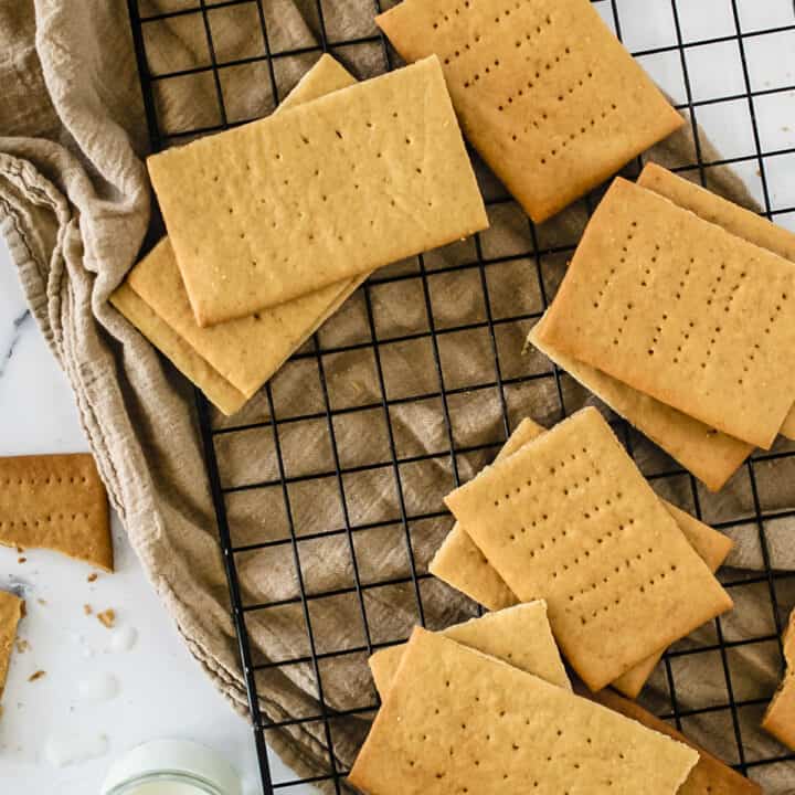 Graham crackers on black cooling rack over taupe towel.