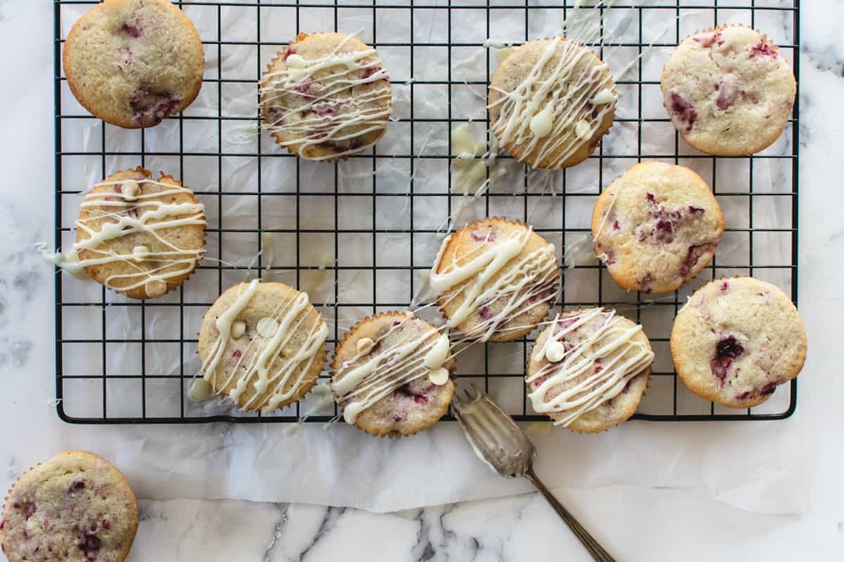 muffins with white drizzle over the tops on a black wire cooling rack