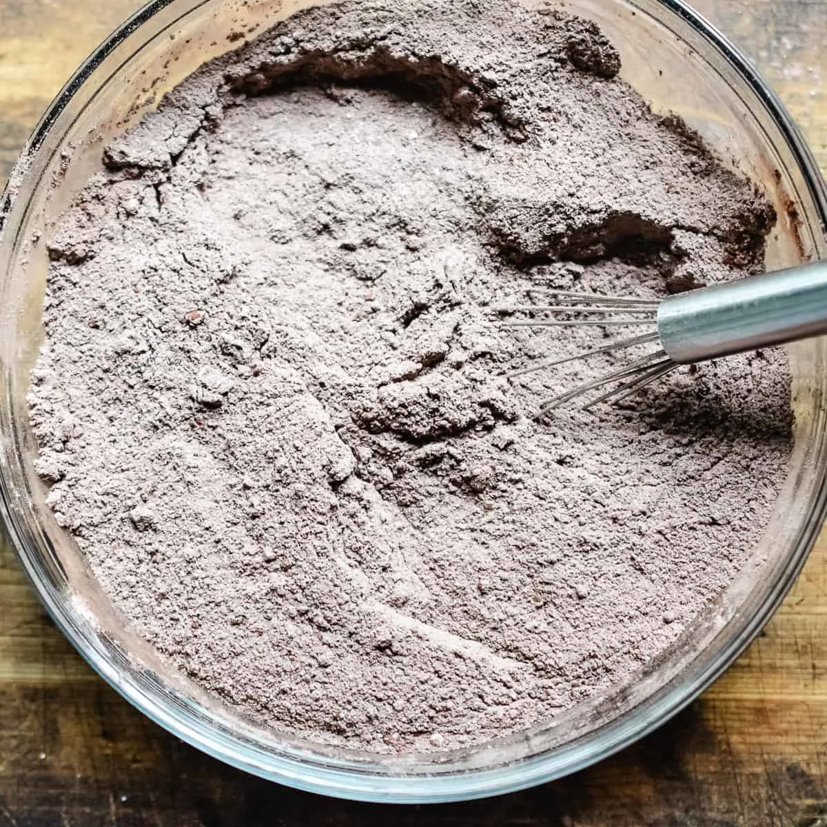 Flour, cocoa powder, sugar, baking powder, baking soda and salt mixed in a bowl.