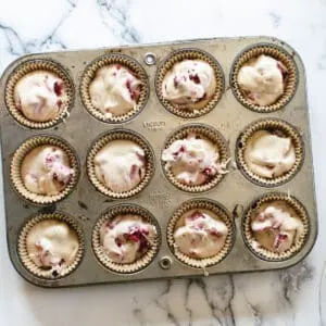 muffin tin filled with white chocolate raspberry batter