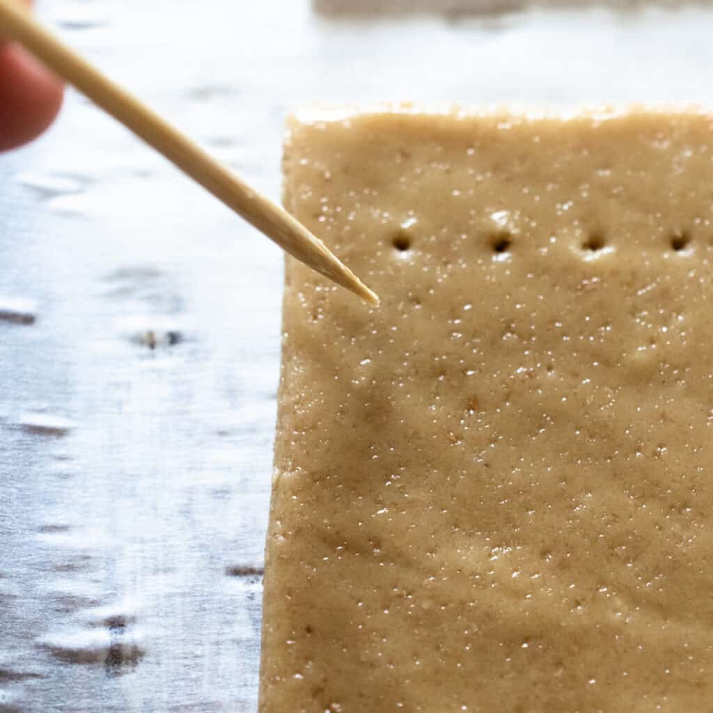 toothpick poking holes in brown rectangle shaped dough