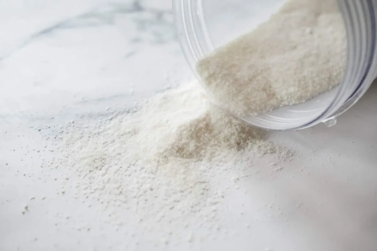 rice flour coming out of a container on its side on a white marble background