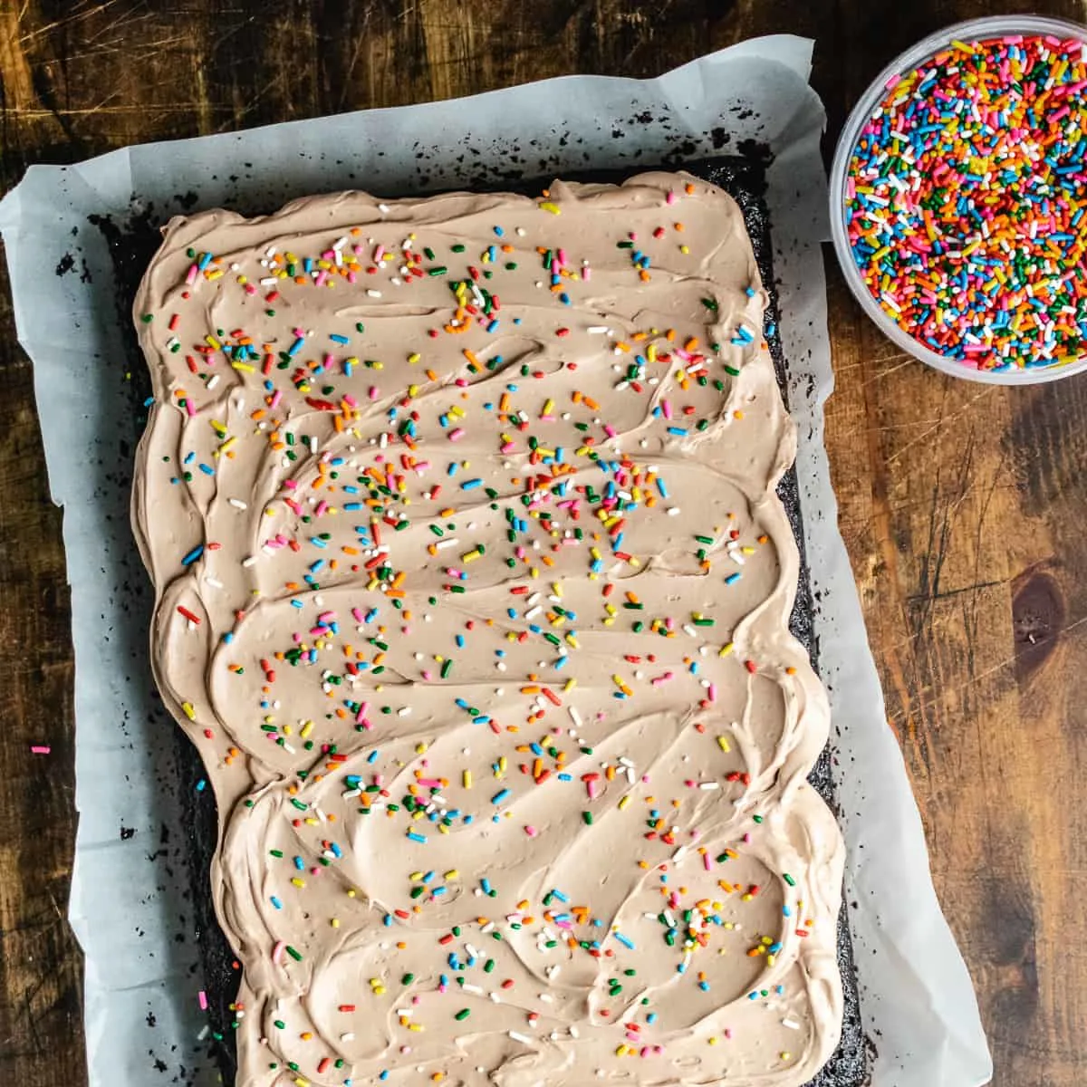 A chocolate cake with chocolate frosting and colorful sprinkles. 