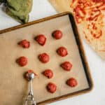 Balls of tomato paste on a baking sheet.