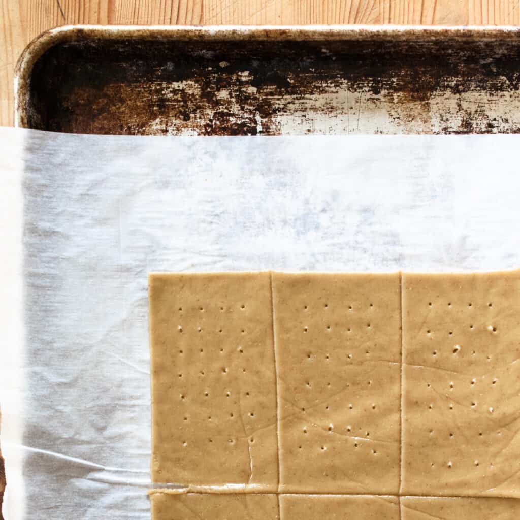 slab of brown dough cut and trimmed into rectangles with holes poked in them on a baking sheet