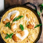 Chicken and orzo in a creamy sauce in a skillet garnished with fresh basil.