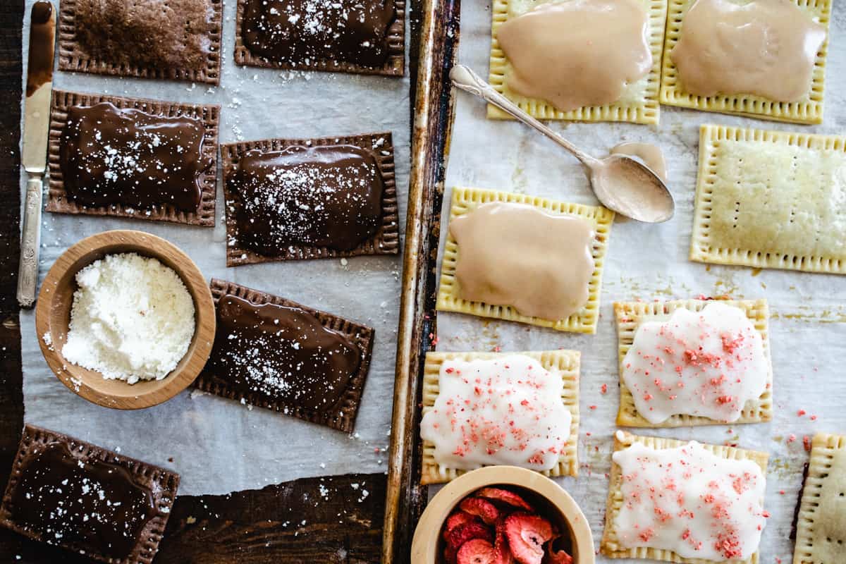 Cinnamon, chocolate and strawberry pop tarts on baking sheets.