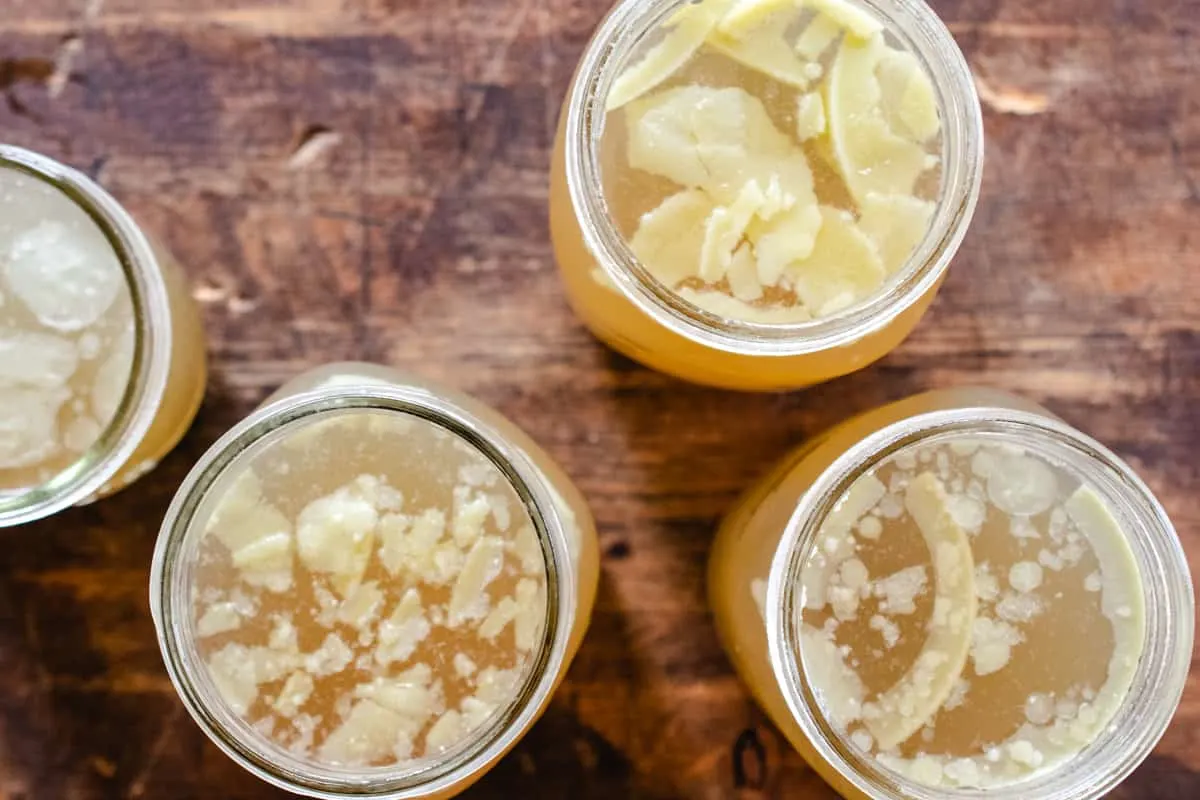 Mason jars of bone broth with solidified fat pieces floating on top.