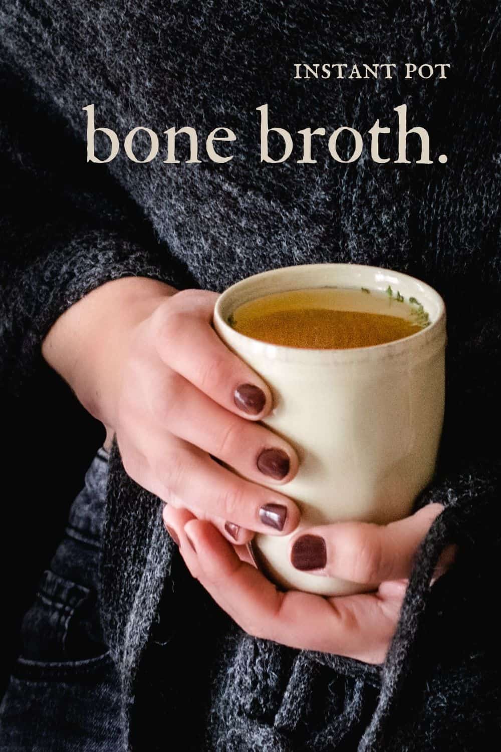 Woman holding a mug with broth sprinkled with herbs.
