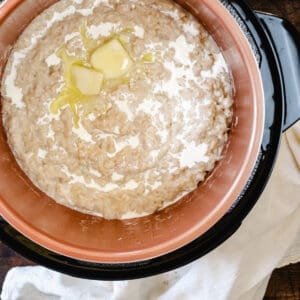 Overhead view inside an opened electric pressure cooker filled with cooked oatmeal.