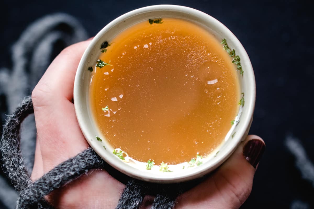 Mug with chicken bone broth and parsley flakes.