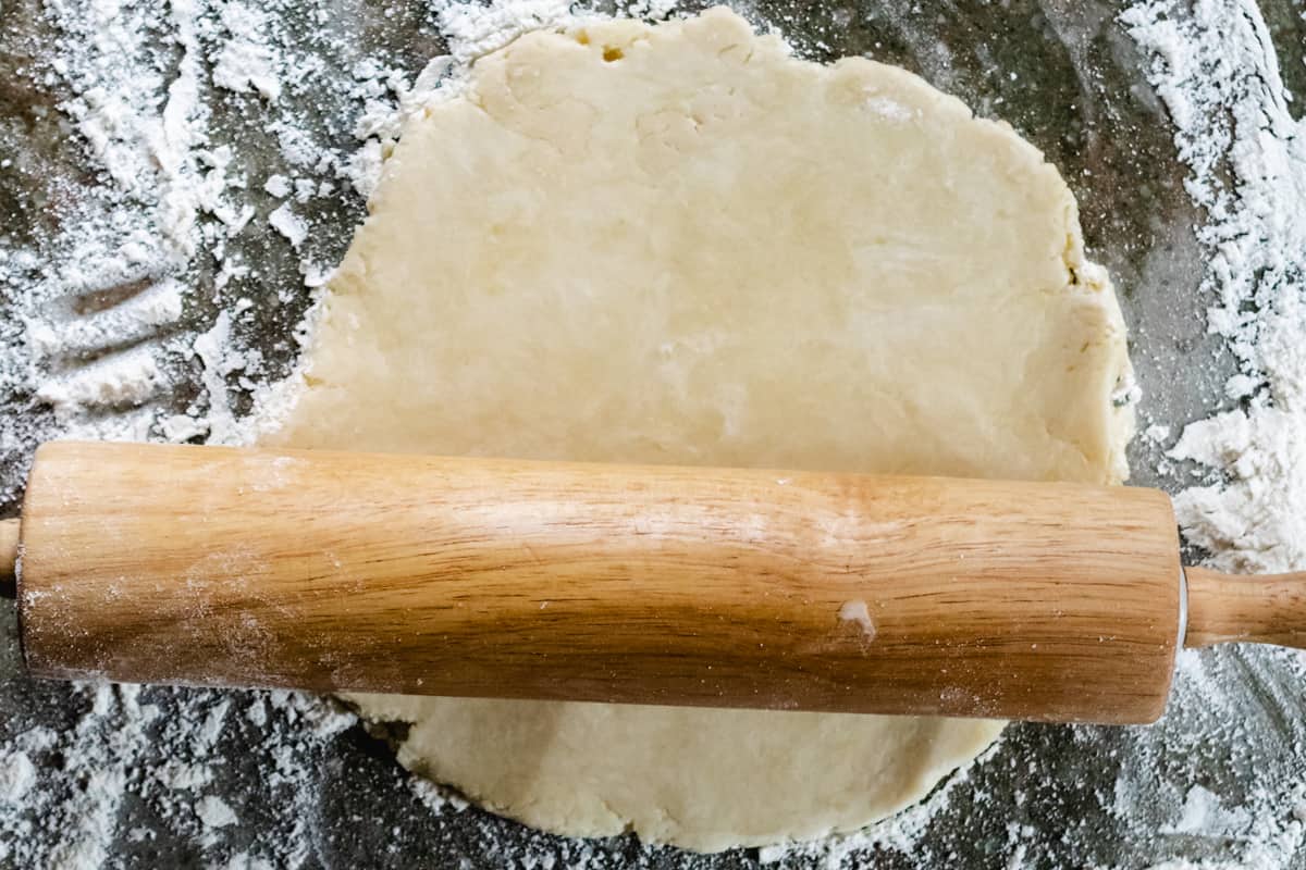 Pie crust being rolled out with a rolling pin.