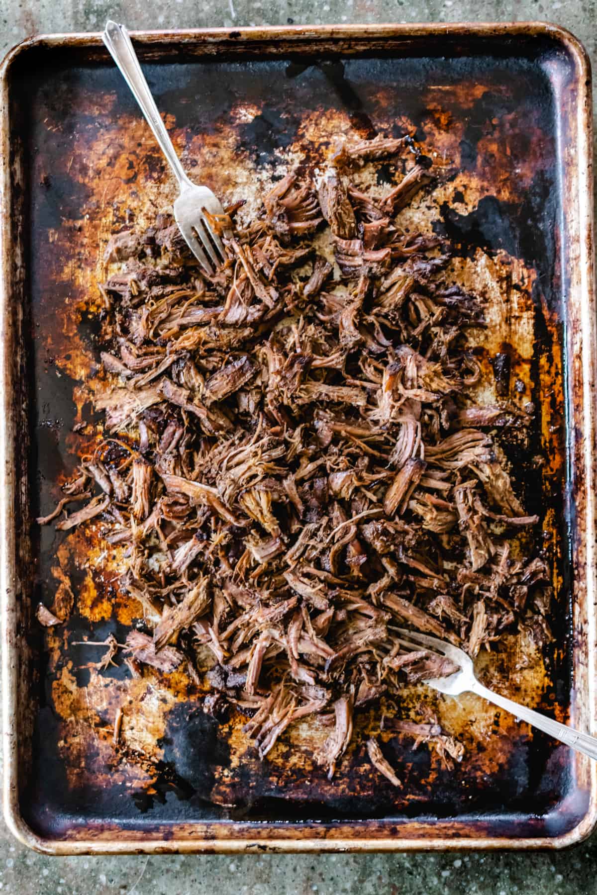 Sheet pan with shredded beef and two forks.