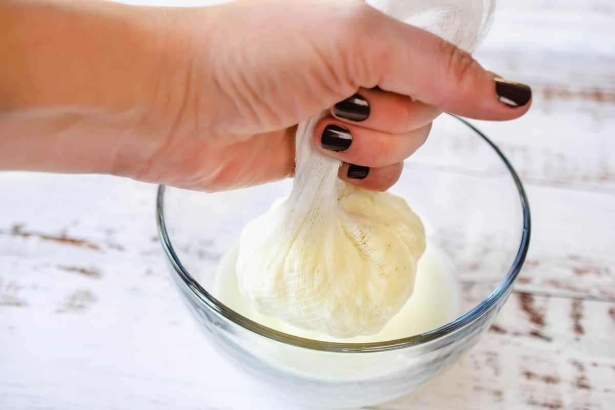 Squeezing butter in a cheesecloth to separate the buttermilk.