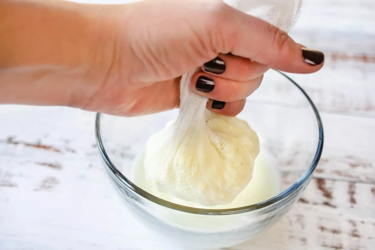 Squeezing butter in a cheesecloth to separate the buttermilk.