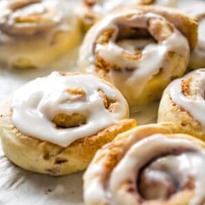 Cinnamon rolls with icing on parchment paper.