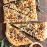 Pizza cut into slices topped with sausage, sage and sweet potato.