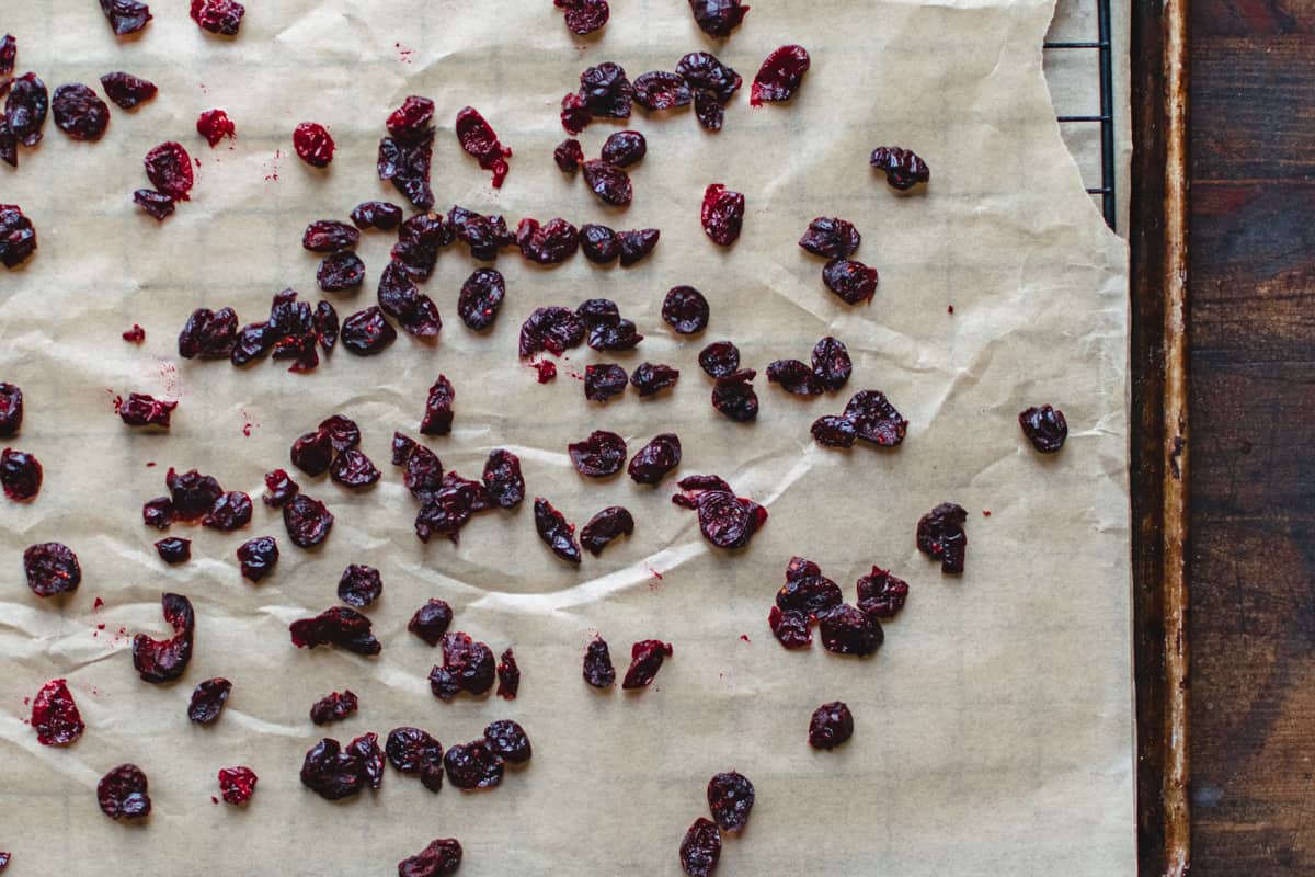 Dried cranberries on a baking rack with parchment paper.