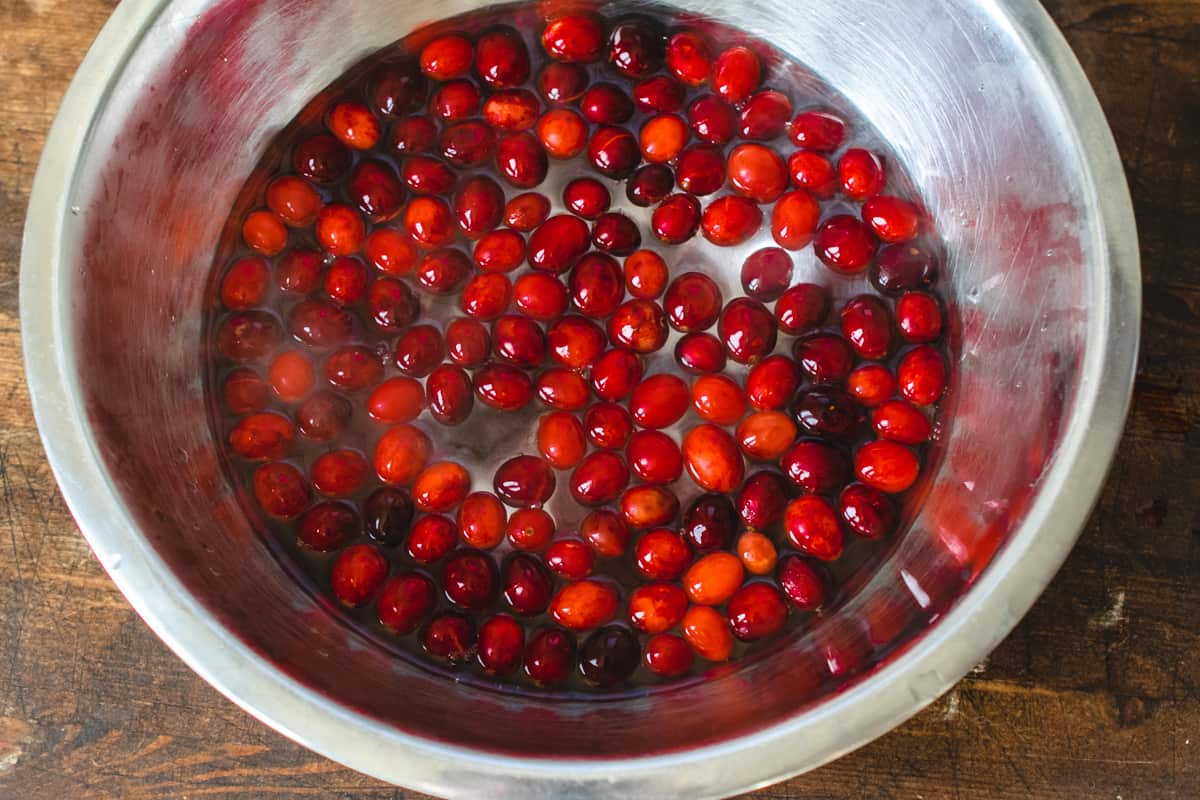 A metal bowl filled with cranberries and water.