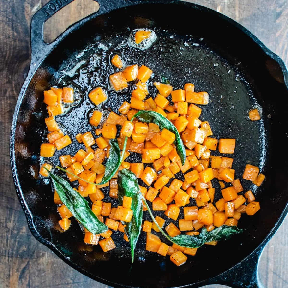 Diced sweet potato and sage being fried in a skillet