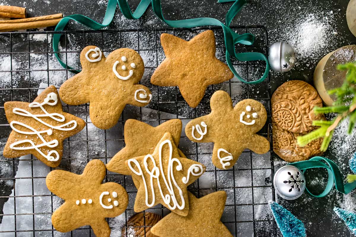Ginger bread man and star shaped gingerbread cookies decorated with white icing on a cooling rack. 