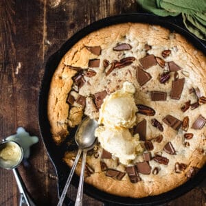 Cast iron skillet with chocolate chunks, pecans and ice cream scoops.