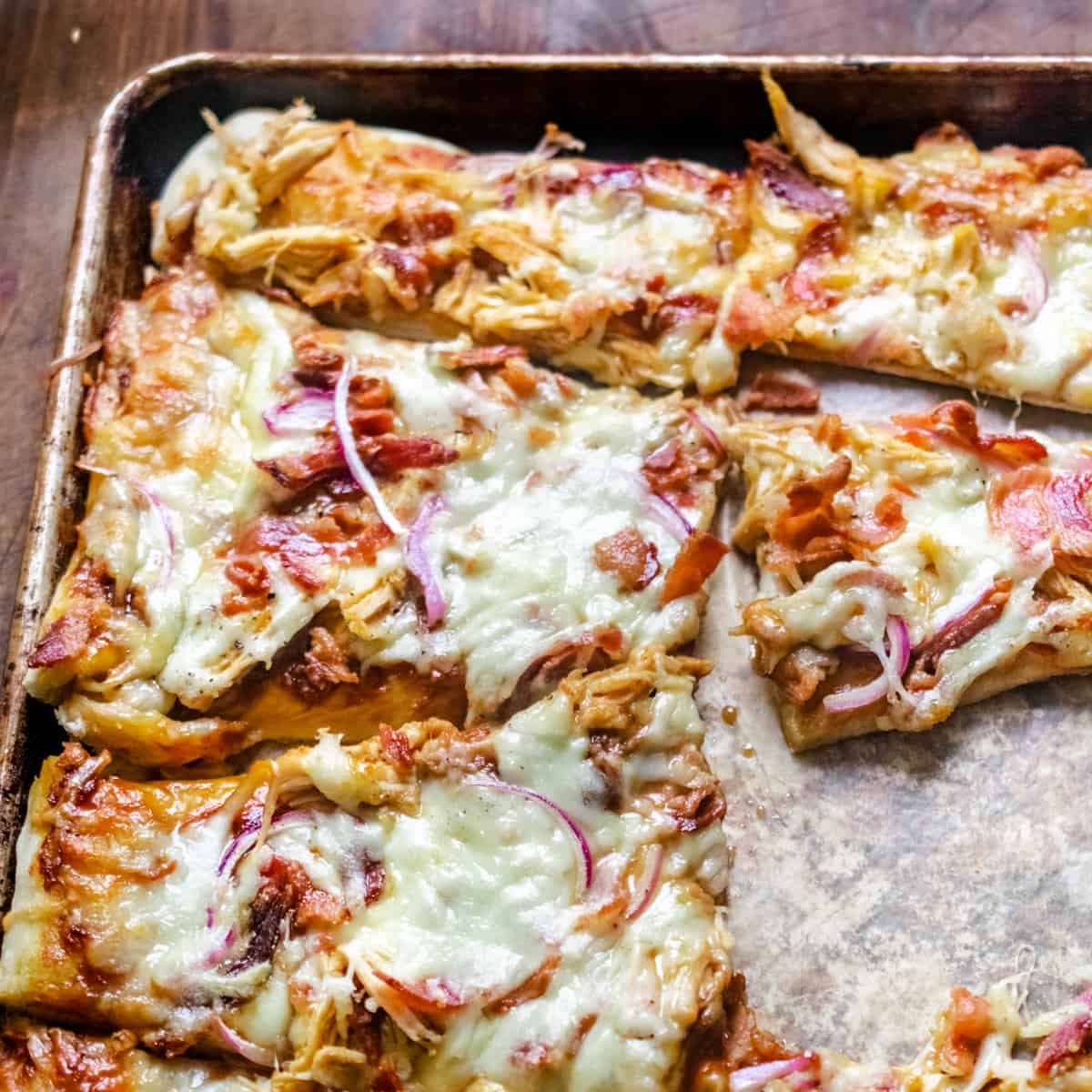 Flatbread pizza with barbecue sauce, cheese, chicken, and red onion.