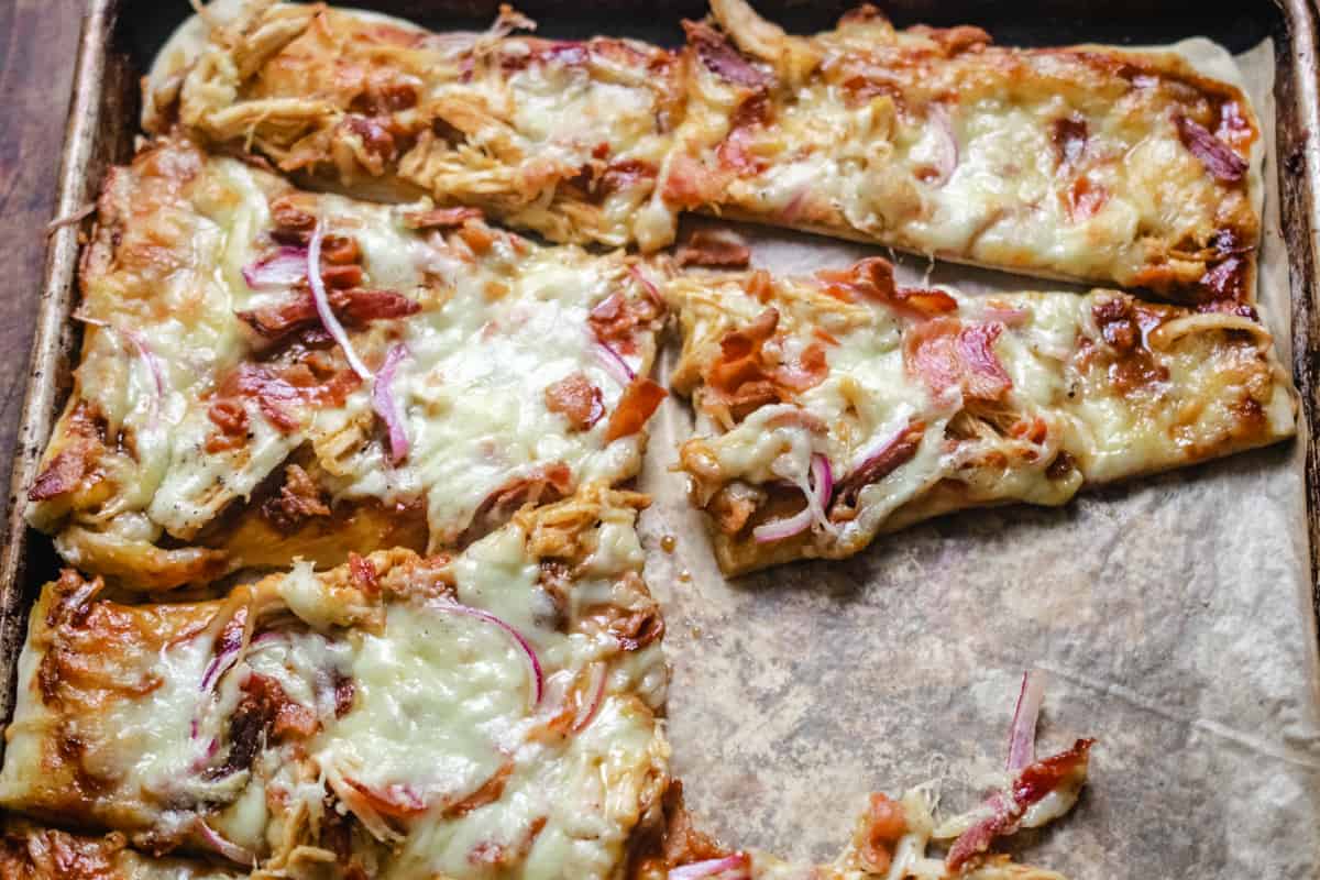 Wedge shaped slices of flatbread topped with cheese, chicken and red onion.