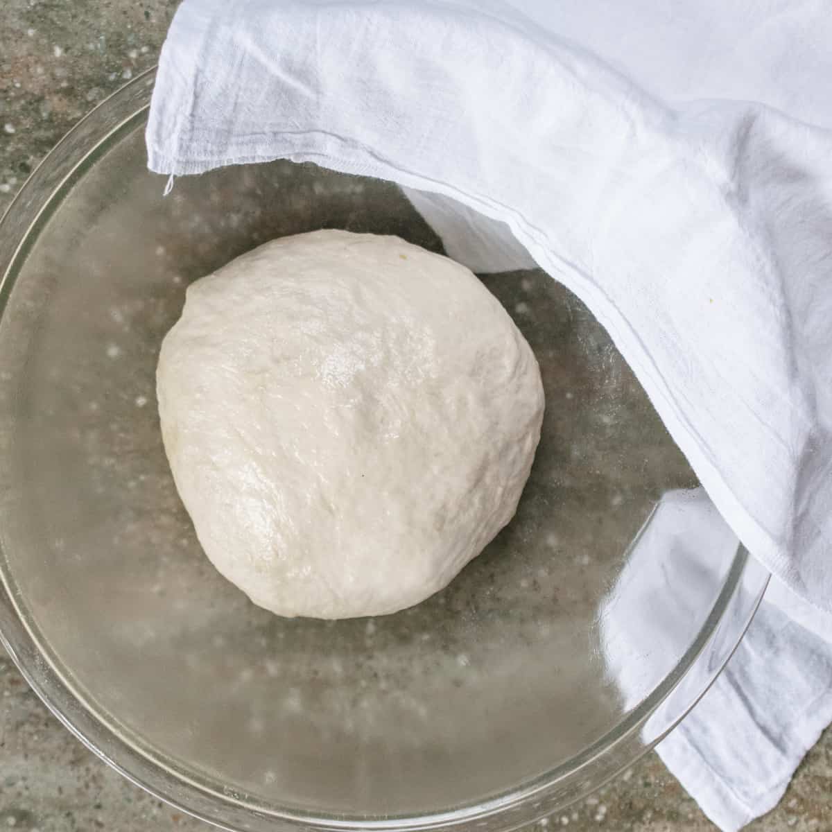 Flatbread dough in a glass bowl.