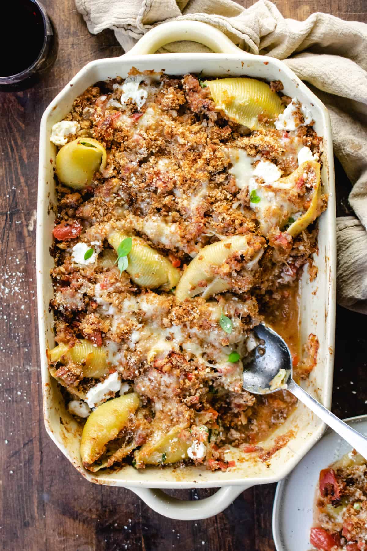 Baked stuffed pasta shells in a casserole dish with a serving spoon.