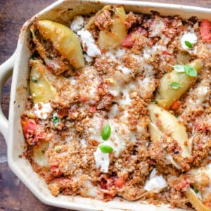 Stuffed pasta shells in a casserole dish with large serving spoon.