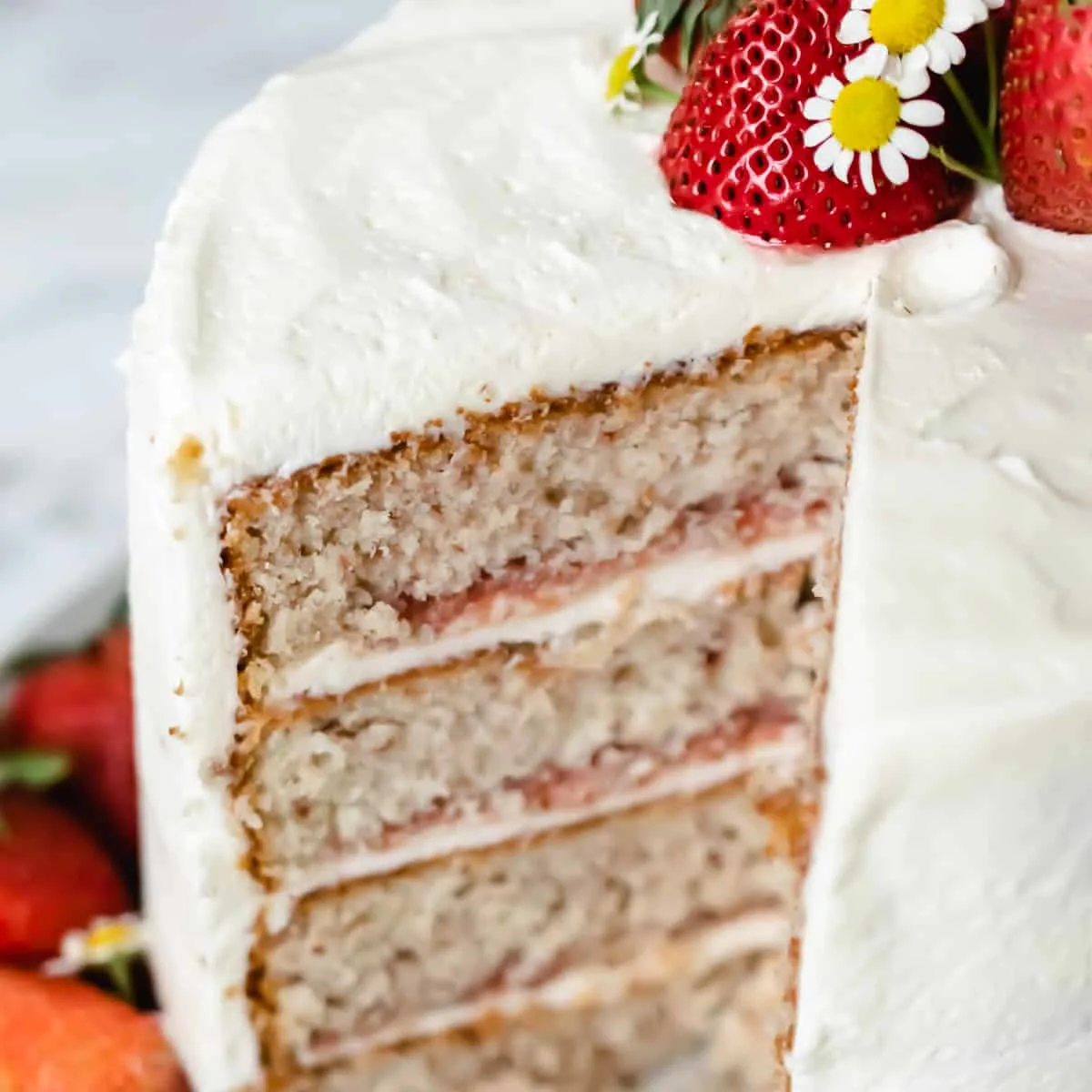 A slice taken out of a strawberry layer cake with strawberry filling.