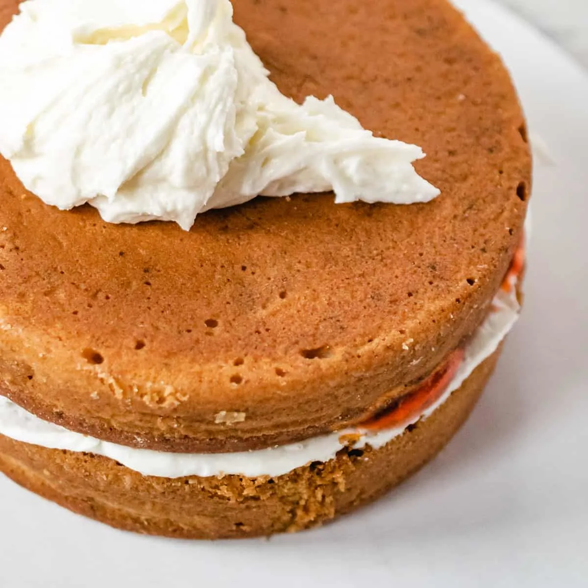 Round cake layers with white frosting with strawberry filling. 