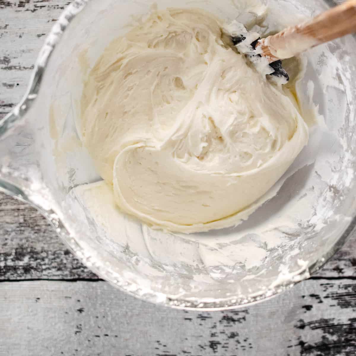 Glass mixing bowl of white buttercream frosting.