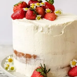 A strawberry layered cake with buttercream frosting, strawberry filling and fresh strawberries.